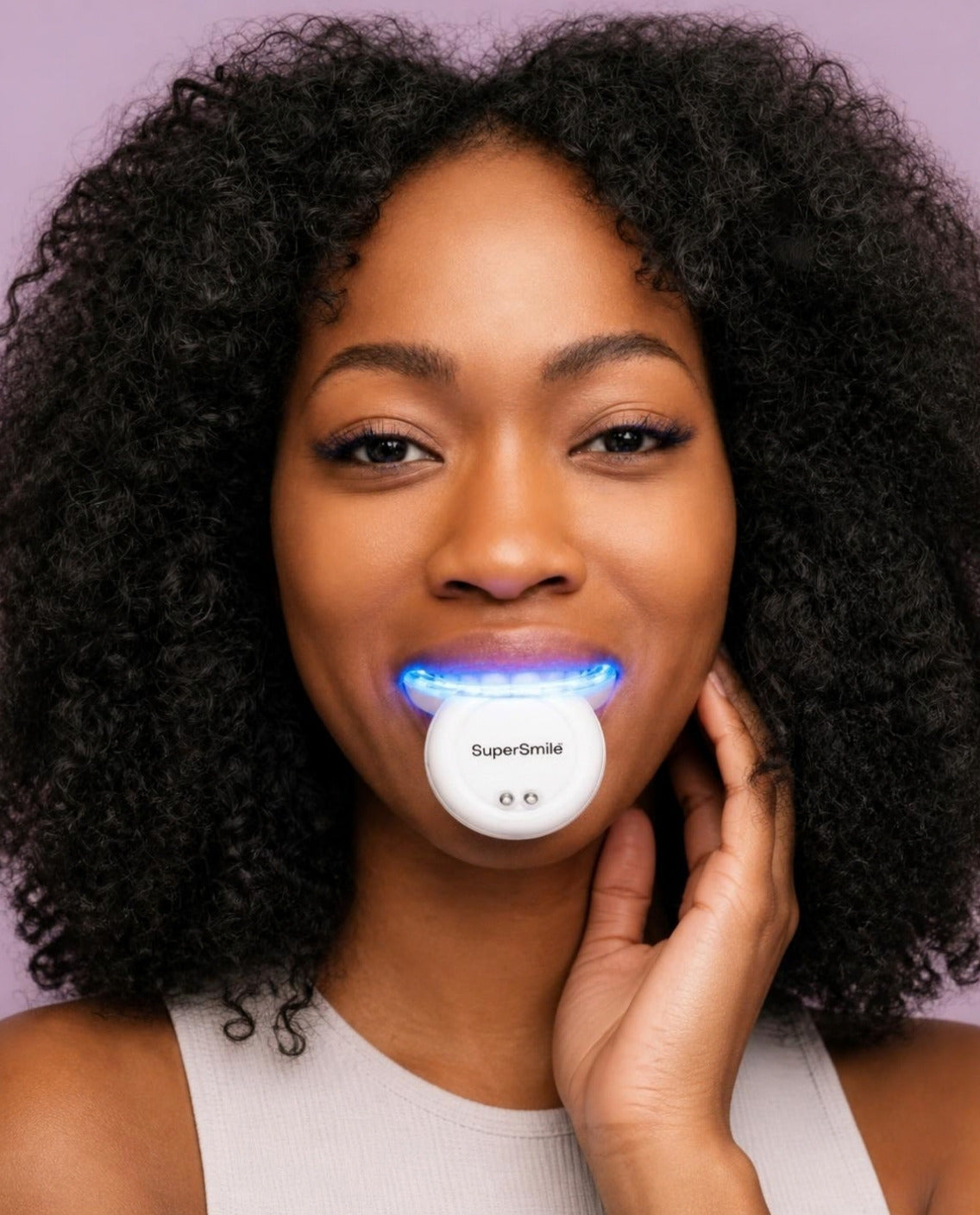 Smiling woman using the SuperSmile LED Light Teeth Whitening Kit