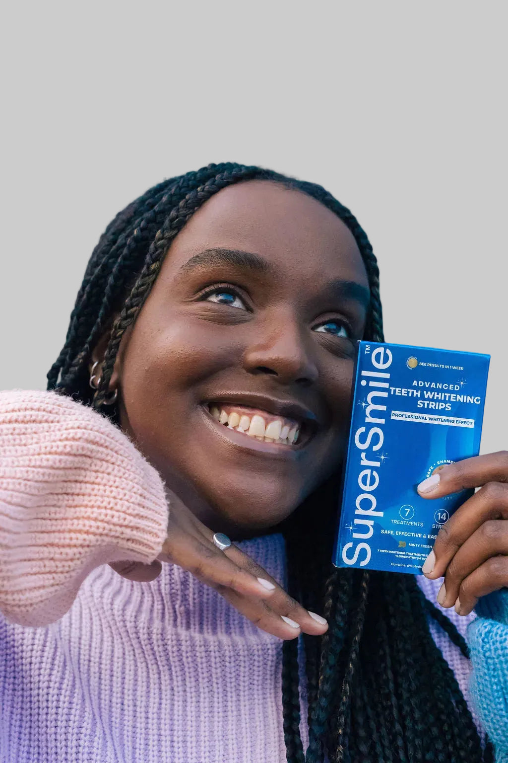 Smiling woman holding SuperSmile Advanced Teeth Whitening Strips
