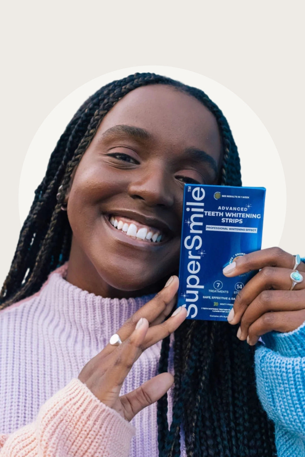 Smiling woman holding SuperSmile Advanced Whitening Strips